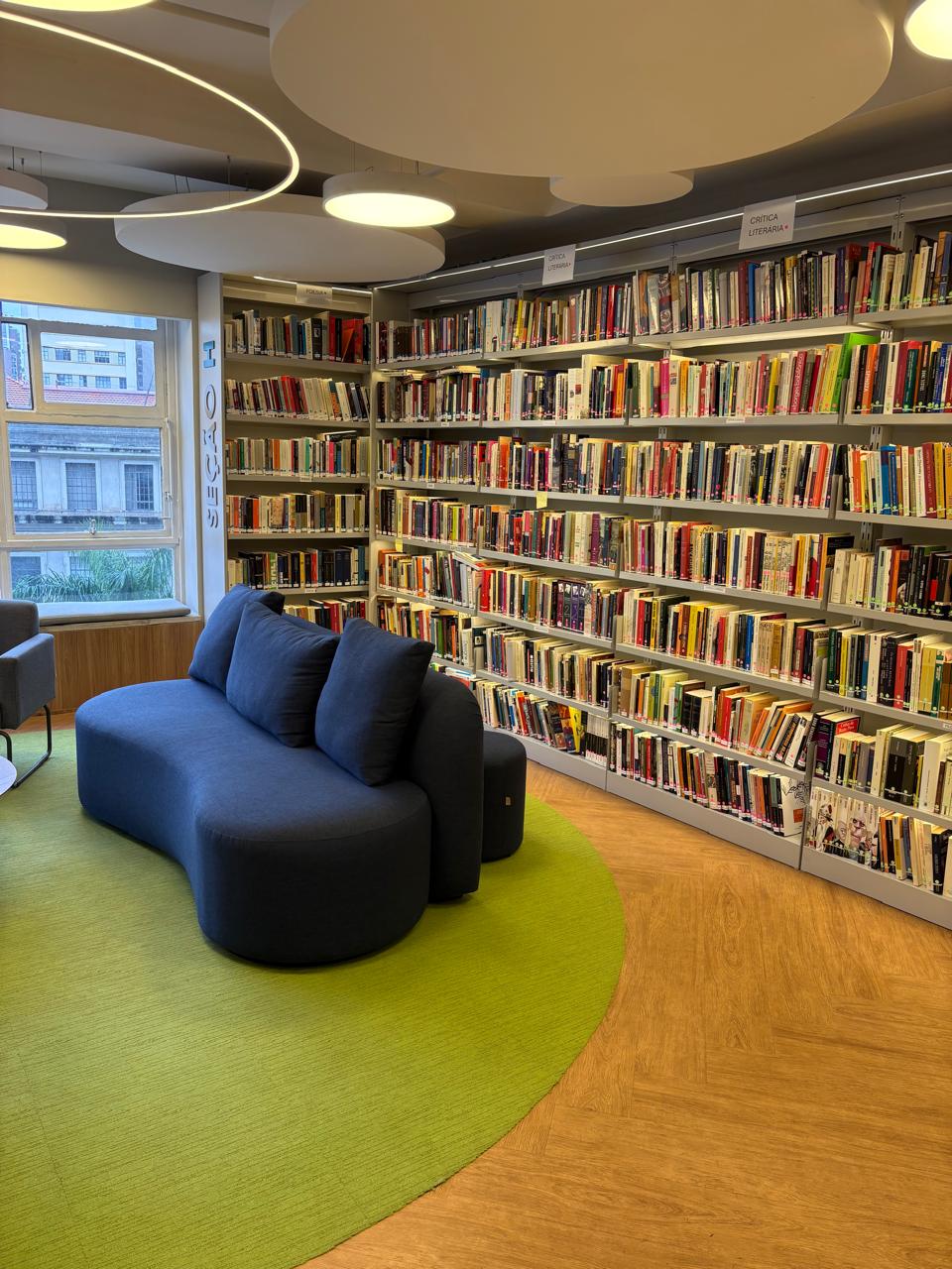 Sofá da área de leitura em frente às estantes da Seção H